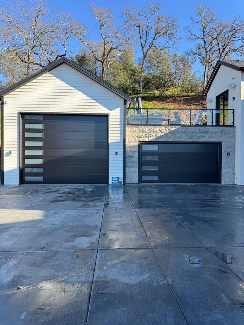 Two dark sectional garage doors with vertical window inserts in El Dorado Hills